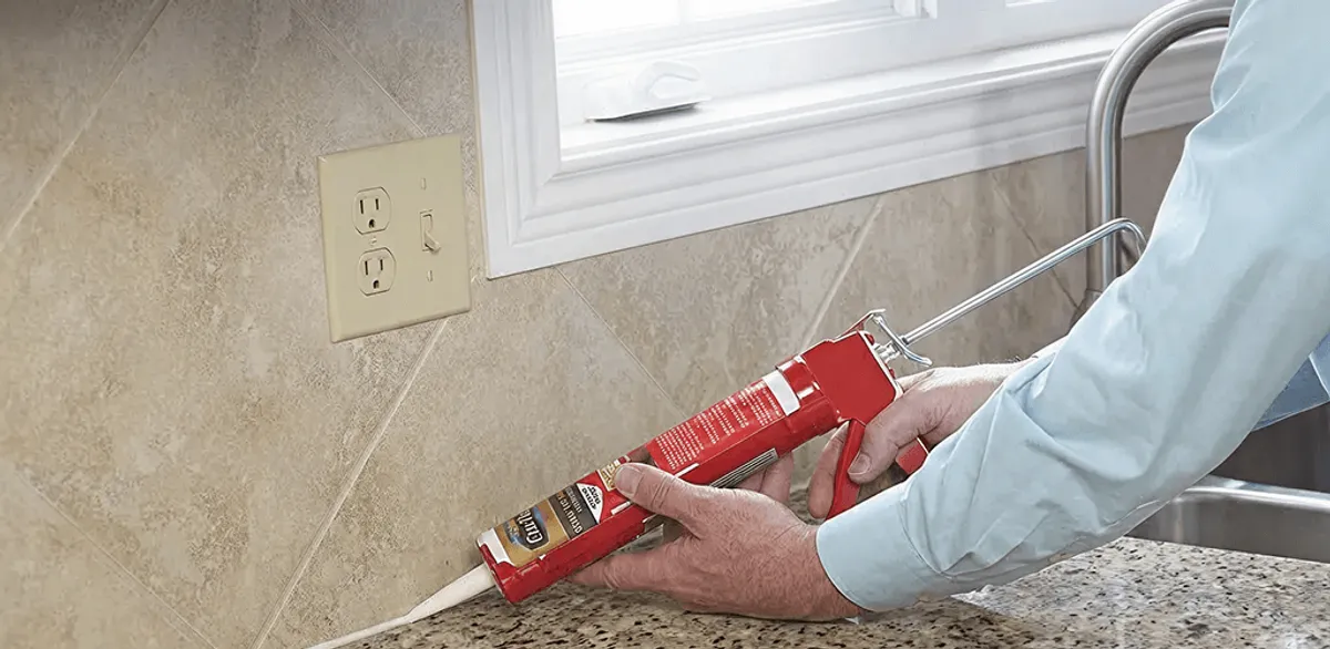 Handyman applying caulk along a kitchen backsplash and countertop seam in Seattle, WA