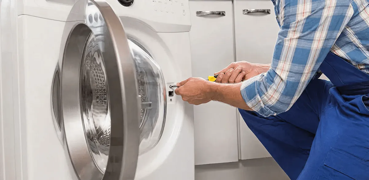Handyman repairing a clothes dryer and checking electrical connections in Seattle, WA